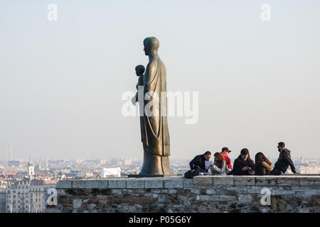 I turisti vicino alla statua in bronzo della Vergine Maria dello scultore Laszlo Matyassy al di fuori del Castello di Buda, affacciato sulla città di Budapest attraverso il fiume Danubio Foto Stock