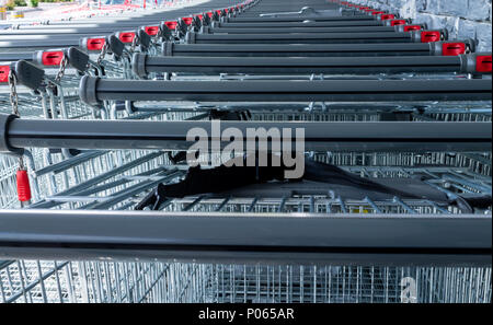 Carrelli della spesa a gettone impilati al di fuori di un supermercato o la vendita al dettaglio di prodotti alimentari in uscita. Foto Stock