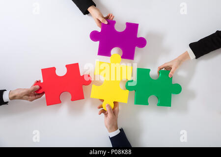 Gruppo di imprenditori risolvere colorato Puzzle sulla scrivania Foto Stock