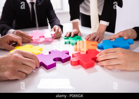 Gruppo di imprenditori risolvere colorato Puzzle sulla scrivania Foto Stock