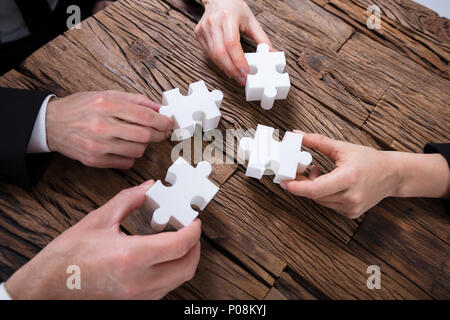 Gruppo di imprenditori risolvendo puzzle sulla scrivania Foto Stock