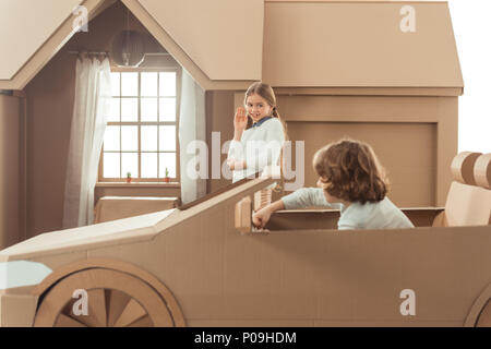 Vista laterale di capretto è arrivato per la ragazza sulla vettura di cartone Foto Stock