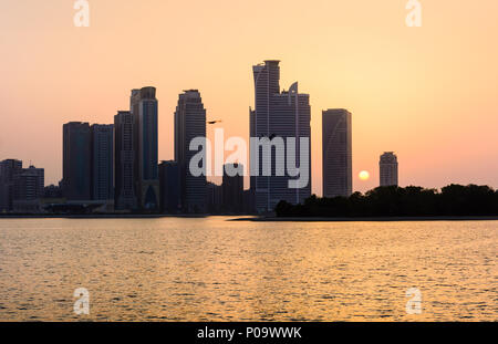 Città moderna di scena al tramonto sul mare di Sharjah Foto Stock