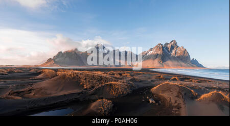 Atmosfera serale alla lunga spiaggia di lava, spiaggia di sabbia nera, dune ricoperte di erba secca, montagne Klifatindur Foto Stock