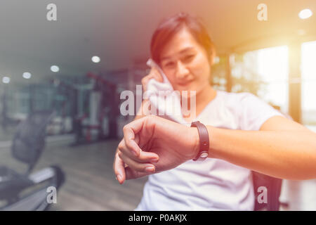 Ragazza sani cercando Tracker Fitness Salute Smart bracciale felice e sorriso in sport club. Foto Stock
