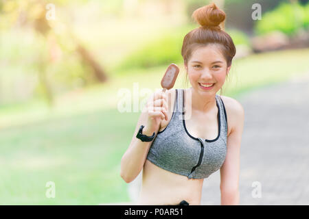 Smile teen di mangiare il gelato al cioccolato nella calda giornata di allenamento al green park Foto Stock