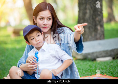 Bella asiatica madre giocando con il suo bellissimo figlio di puntamento a mano a guardare Future Concept. Foto Stock