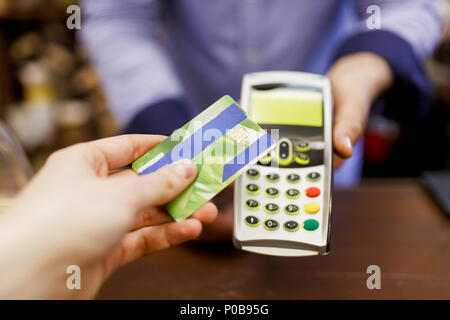 Immagine del compratore con la carta di credito e il venditore con il terminale in mano Foto Stock