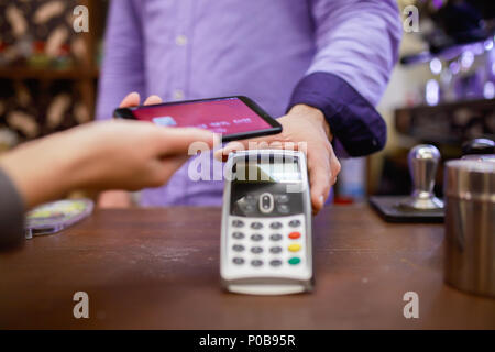 Foto del venditore man con il terminale e il compratore con lo smartphone Foto Stock