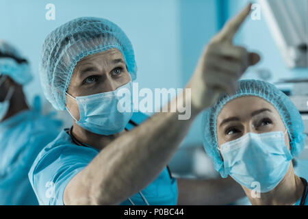 Medico puntando su qualcosa in sala operatoria Foto Stock