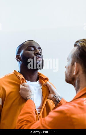 Prigioniero minacciando african american cellmate isolato su bianco Foto Stock