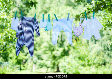 Vestiti del bambino su stendibiancheria in giardino Foto Stock