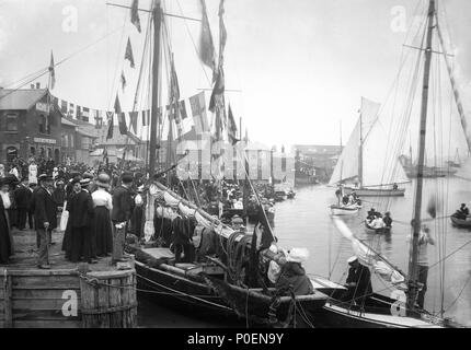 . Inglese: una vista di fronte Pearson's Quay lungo la riva del fiume Colne a Rowhedge durante un festival non identificato. Una vista guardando verso nord attraverso Pearson's Quay lungo la riva del fiume Colne a Rowhedge durante un festival non identificato. Sulla sinistra si vede l'Albion public house, con l'anchor pub a metà distanza attraverso l'armamento di varie imbarcazioni a vela a fianco della banchina. In primo piano si vede una Colchester registrato trawler, vestito nel complesso con i visitatori a bordo. Taglierine e barche a remi sono sull'acqua di essere guardato da grandi folle di ben vestito spettatore Foto Stock