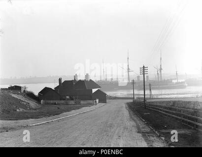 . Inglese: una vista guardando oltre la foreshore di 'Shotley Gate' attraverso il Fiume Stour verso Harwich una vista guardando verso il basso una lieve pendenza alla foreshore di 'Shotley Gate' attraverso il Fiume Stour verso Harwich. I bracci di Bristol si trova sulla sinistra della strada di fronte al fiume. La formazione di navi " Gange" (ex-'Minotaur') (1863), e 'Caroline' (1882) e il quartiere di poppa di 'Gange II" (ex-'Agincourt') (1865) può essere visto in mezzo la distanza di ormeggi. Una vista guardando oltre la foreshore di 'Shotley Gate' attraverso il Fiume Stour verso Harwich . circa agosto 1907. Smiths Suitall Ltd 241 a vie Foto Stock