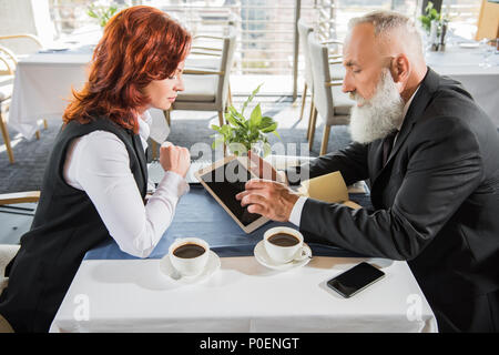 Colleghi di lavoro avente incontro nel ristorante e guardando il tablet Foto Stock