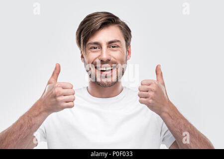 Bel uomo sorridente mostra Thumbs up, isolato su bianco Foto Stock