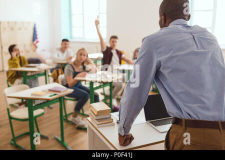 Vista posteriore di African American Maestro e scolaro con braccio fino in aula Foto Stock