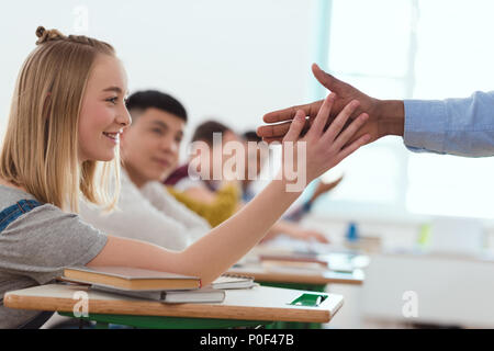 Immagine ritagliata di African American insegnante tenendo alta cinque a sorridere teenage schoolgirl Foto Stock