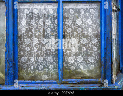 Vecchia casa abbandonata con weathered telai di finestre e tendine. Foto Stock