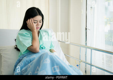 Asian giovane donna pazienti giacente in camera. Pazienti asiatici aveva forti mal di testa in ospedale. Foto Stock
