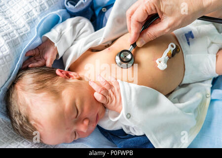 Utilizzando uno stetoscopio per controllare la salute del neonato ragazzo in ospedale Foto Stock