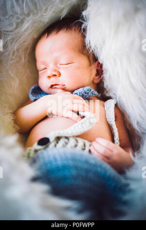 Un neonato Bambino addormentato in blu e grigio in maglia di bow tie e pantaloni Foto Stock