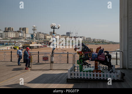 Gli ospiti in piedi vicino fiera giro sul palazzo di Brighton Pier e Brighton East Sussex, England, Regno Unito Foto Stock