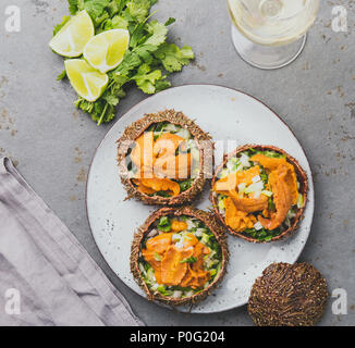 Aperto fresco ricci di mare. Il caviale di ricci di mare con cipolla, il coriandolo e il limone all'interno del guscio di ricci di mare. Vista dall'alto. Foto Stock