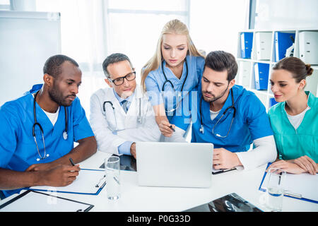 Multietnica focalizzato team di medici e di brainstorming con laptop Foto Stock