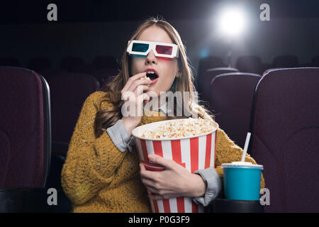 Excited donna occhiali 3d mangiare popcorn e guardare film per il cinema Foto Stock