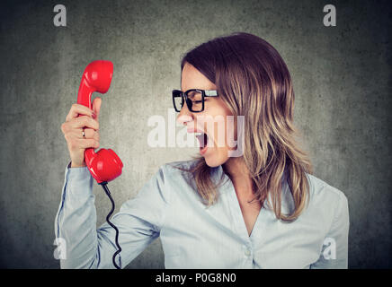 Ritratto di un giovane arrabbiato business donna urlare contro il telefono rosso Foto Stock