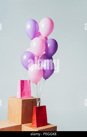 Rosso e rosa shopping bags con fascio di palloncini isolato su bianco, estate concetto di vendita Foto Stock