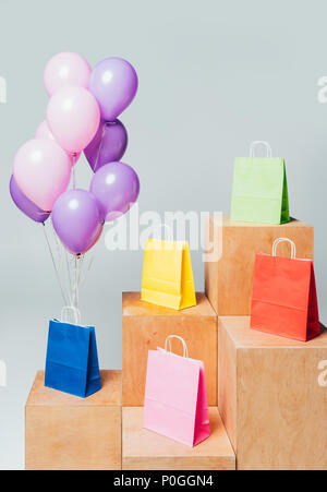 Bundle di rosa e viola palloncini vicino a sacchetti di carta su sorge isolato su bianco, estate concetto di vendita Foto Stock