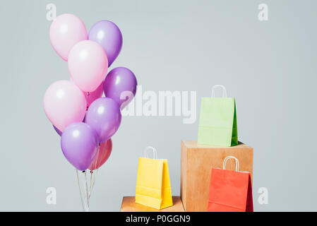 Bundle di rosa e viola palloncini vicino a shopping bags su sorge isolato su bianco, estate concetto di vendita Foto Stock