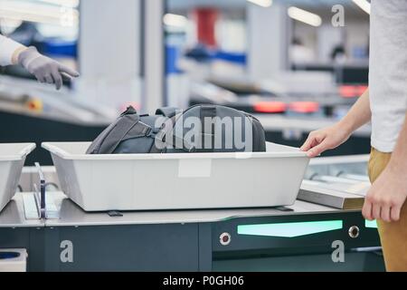 Controllo sicurezza in aeroporto. Giovane uomo (traveler) in attesa di comando raggi x i suoi bagagli. Foto Stock