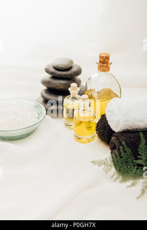 Vista ravvicinata della disposizione di spa gli accessori per il trattamento con olio essenziale, ciottoli e sale su sfondo bianco Foto Stock