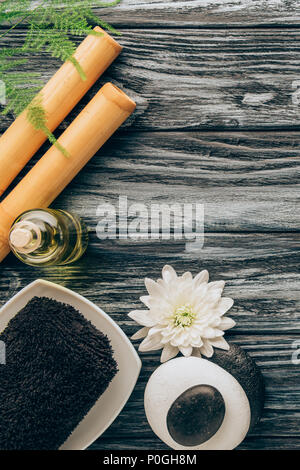 Lay piatto con spa e trattamenti di massaggio disposizione con asciugamano, olio essenziale, ciottoli e crisantemo fiore sul tavolo in legno Foto Stock