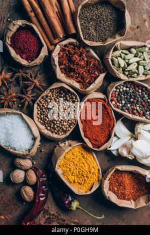 Vista superiore del sale, fiocchi di peperoncino e pepe in polvere in sacchi di carta sul tavolo Foto Stock