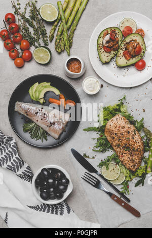 Vista superiore del sano con piatti a base di pesce e di carne e di avocado su grigio Foto Stock