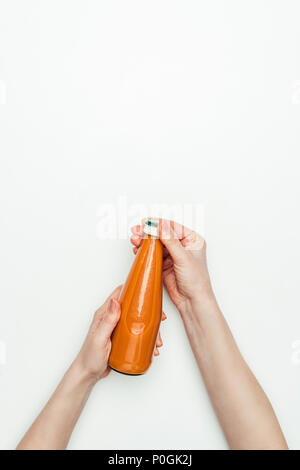 Immagine ritagliata della donna di aprire una bottiglia di succo di carota isolato su bianco Foto Stock