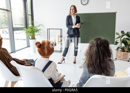 Giovani insegnanti di sesso femminile che spiega la lezione agli studenti in aula Foto Stock