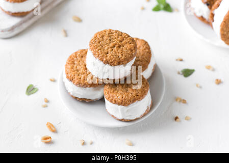 Panini di gelato con i dadi e i cookies integrali. Gelato di vaniglia fatto in casa panini su sfondo bianco. Foto Stock