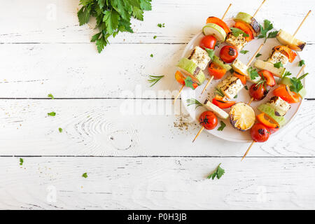 Grill vegetariano. Spiedini vegetariani con il formaggio halloumi e verdure su sfondo bianco, copia dello spazio. Foto Stock