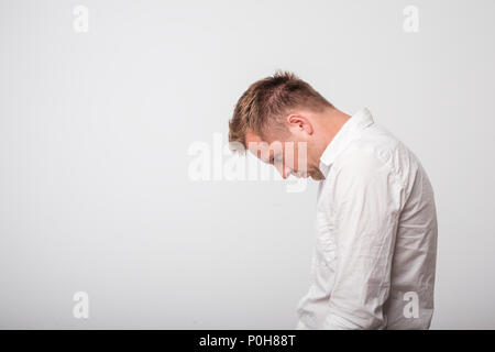 Triste europea giovani caucasici Uomo in camicia bianca guardando verso il basso Foto Stock