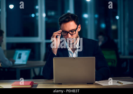 Giovane imprenditore stare alzati fino a tardi a lavorare. Foto Stock