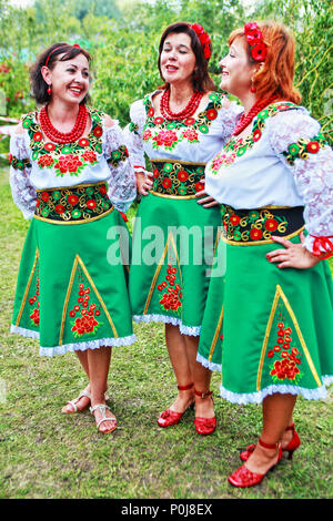 Tre donne ucraine in costumi tradizionali ricamati cantano alla fiera agro di Sorochintsi nella regione di Poltava nell'Ucraina centrale nell'agosto 2016. Foto Stock