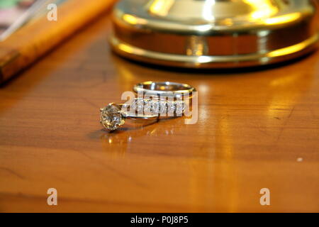 Impegno anello diamante e due anelli di nozze sul comò pronto per il giorno del matrimonio cerimonia Foto Stock
