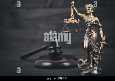 Il diritto e la giustizia, il concetto di legalità, bilancia della giustizia, giudice martello, Justitia, Lady giustizia su un nero lo sfondo di legno. Foto Stock