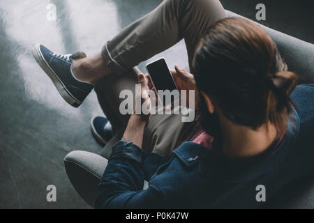 Vista superiore dell'uomo con i capelli bun utilizza lo smartphone Foto Stock
