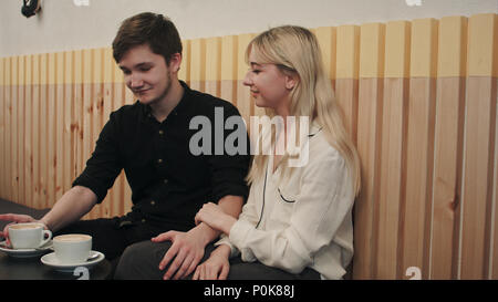Carino coppia felice gustando una tazza di caffè mentre su una data ad un cafe Foto Stock
